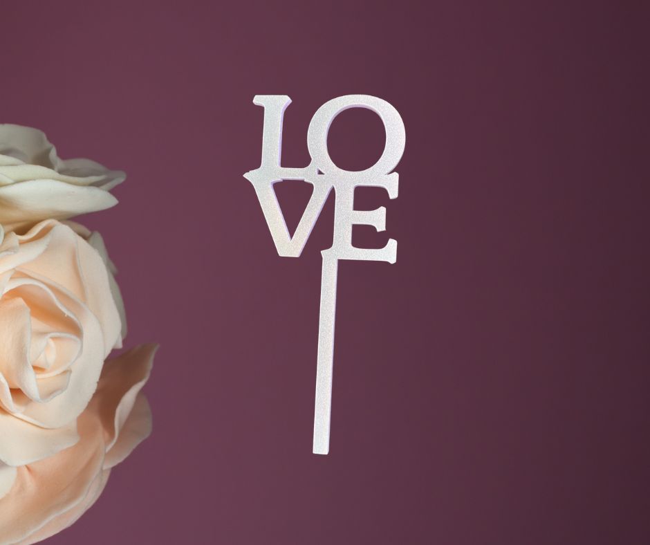Decorative 'LOVE' cake topper with a rose on a purple background